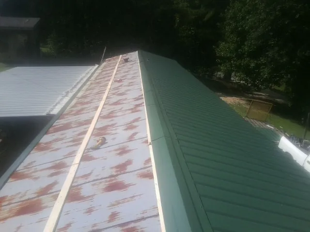 Old rusted panels beside newly installed green metal roofing — Wind Damage Roof Repair by Roofing Brothers in Ramona