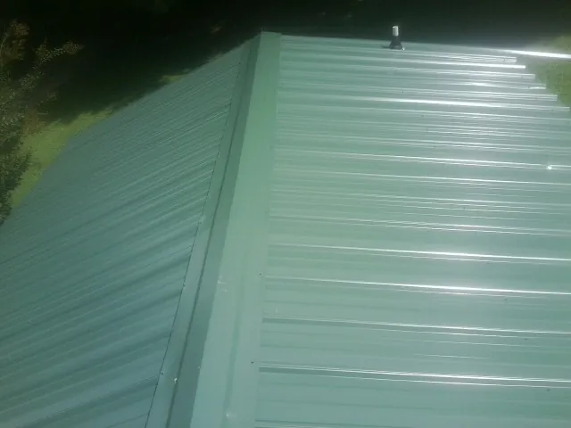 New green metal panels meeting at the ridge of a roof — Flat Roof Repair work by our crew in Ramona