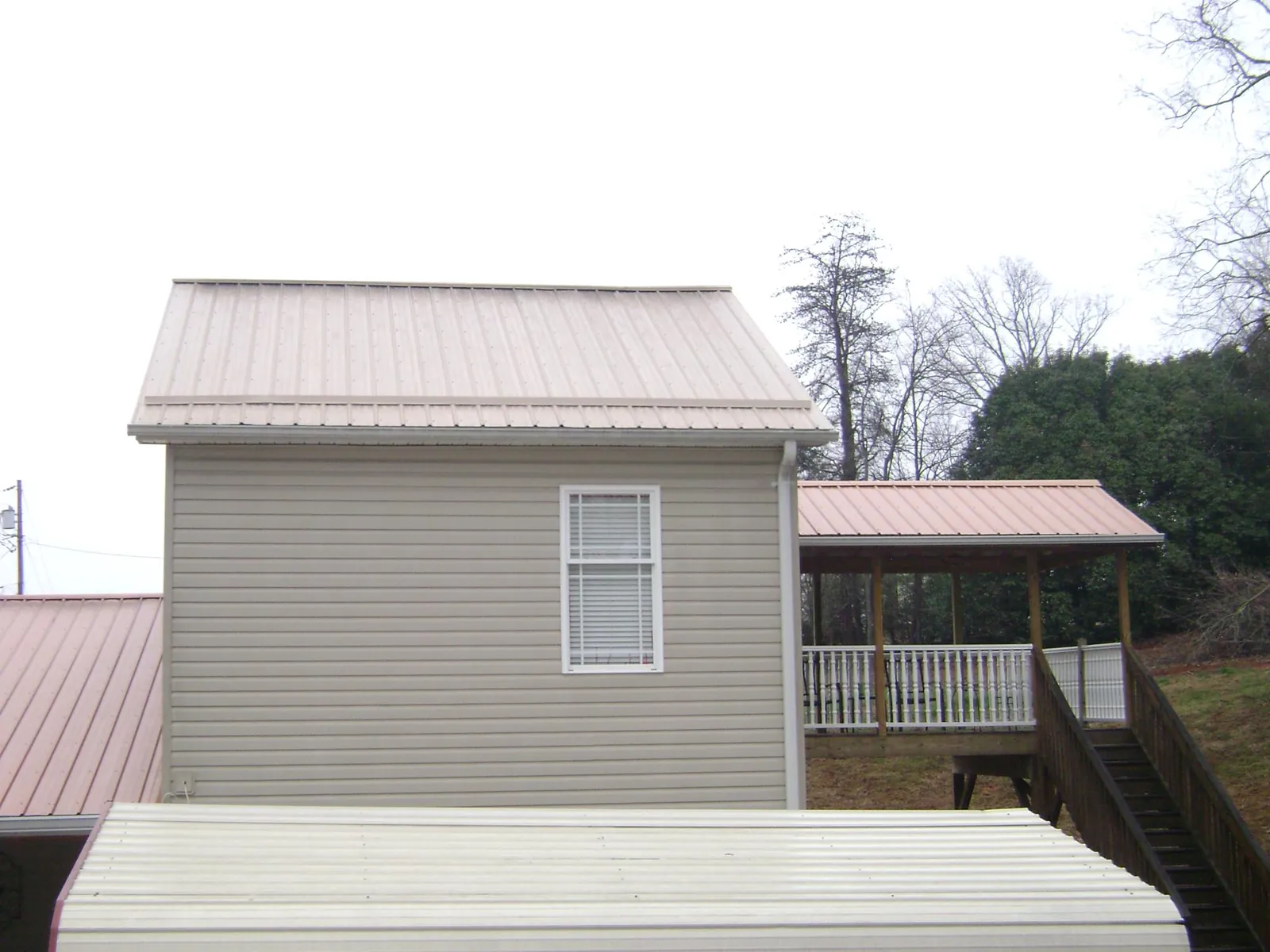 Tan metal roofs on a two story addition and attached porch, from a Roof Replacement job in Ramona