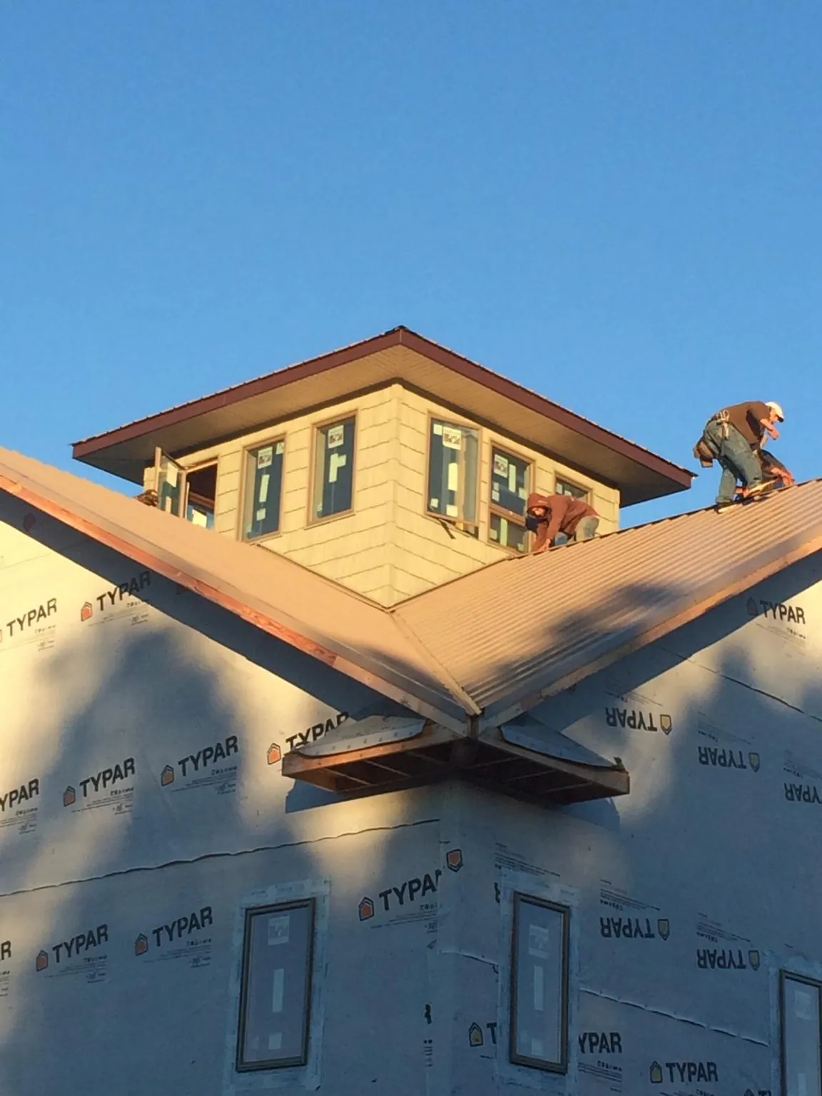 Roofers working around a rooftop cupola on a new metal roof at sunset — Roof Waterproofing in Ramona by Roofing Brothers